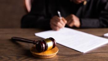 gavel on desk and judge's hands singing paper