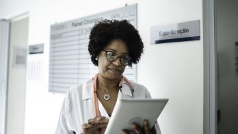 Female doctor reviews information on a tablet in a hallway