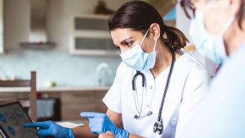 Two medical researchers in a lab look at information on a laptop