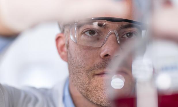 Lab worker looking at beaker