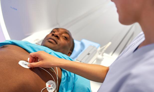 Technician puts ECG stickers on the chest of personabout to enter an MRI machine