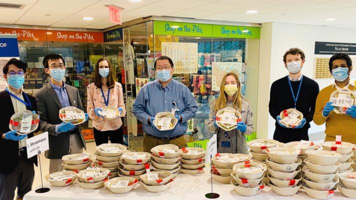 Brigham Digital Innovation Hub team members stand around packaged meal containers on a table