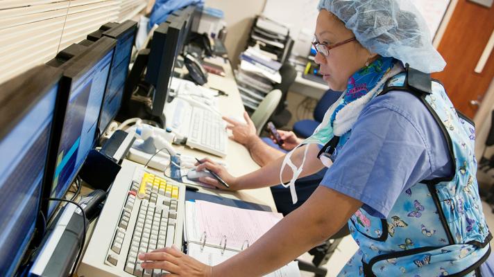 person in PPE at computer, health IT