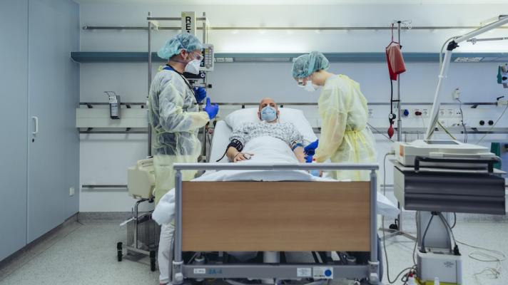 Two staff treating an ICU patient in bed