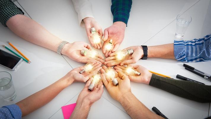 Circle of hands holding lightbulbs