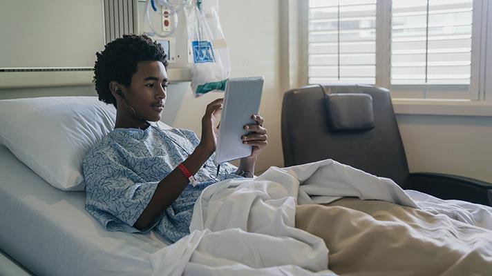 Patient using tablet in bed.