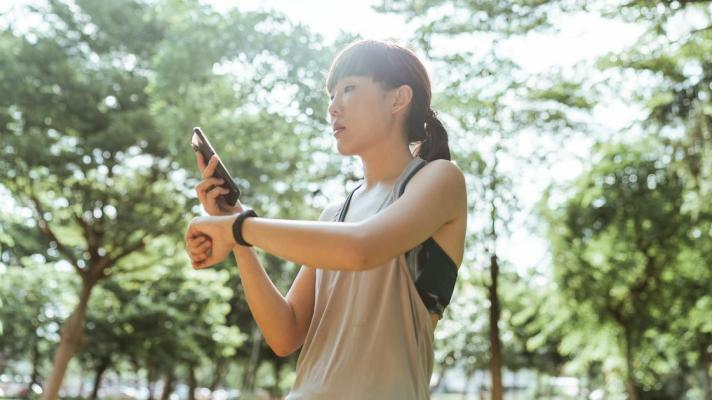 A person checking their smartwatch-tracked fitness data on their smartphone.