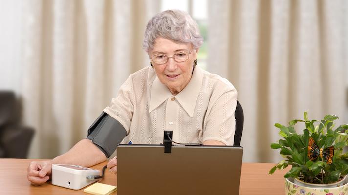 Senior using telemedicine blood pressure cuff.