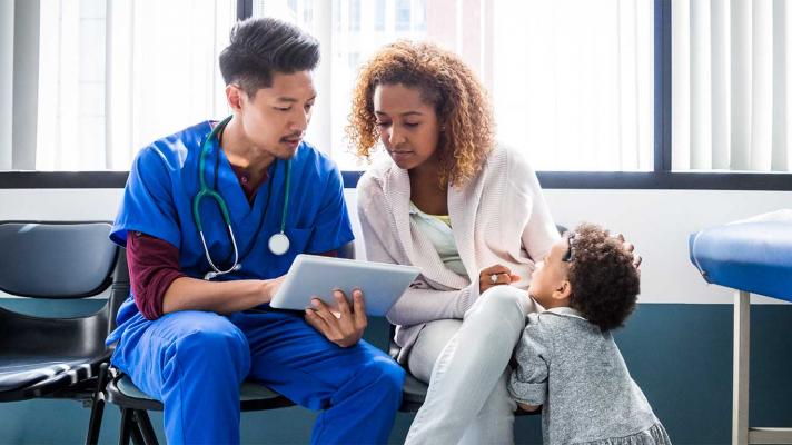 Healthcare worker showing tablet to patient and child